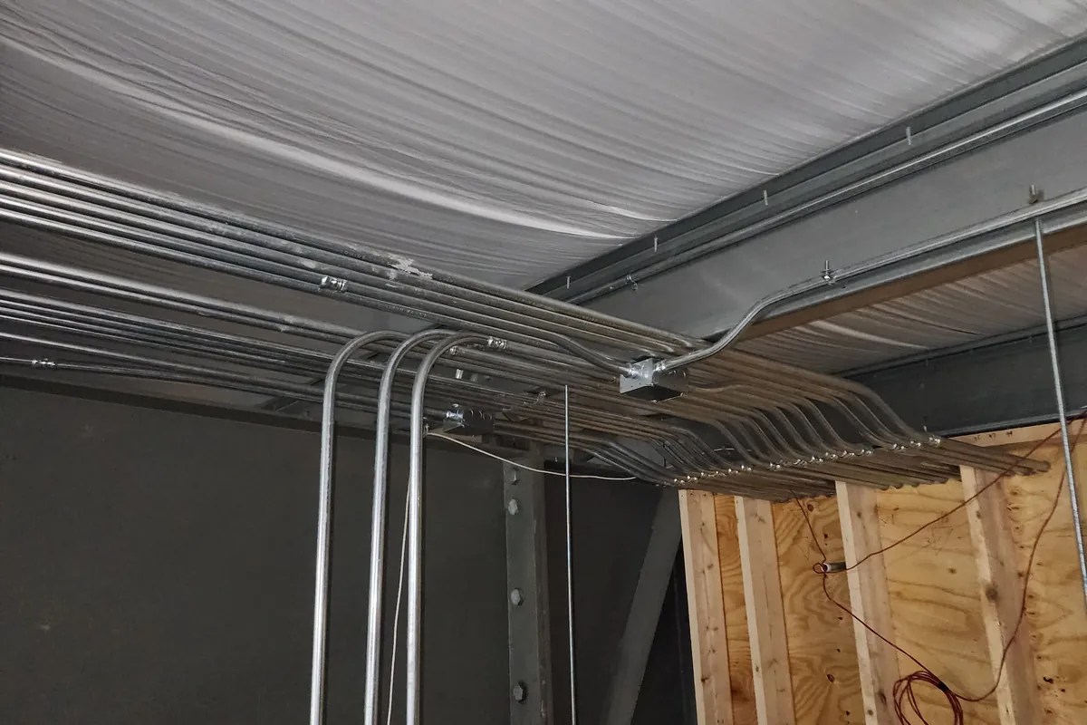 Interior of a new pole building with steel ceiling and conduit run on a post