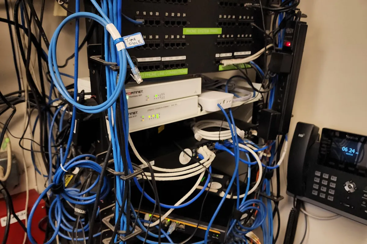 Comms room with patch panels, network switches and dense unmanaged cabling