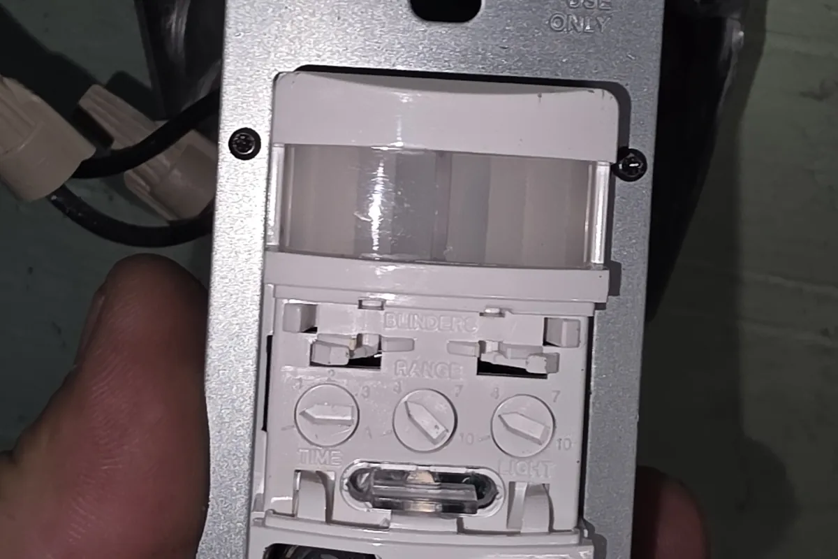 Occupancy sensor switch held in front of its mounting box