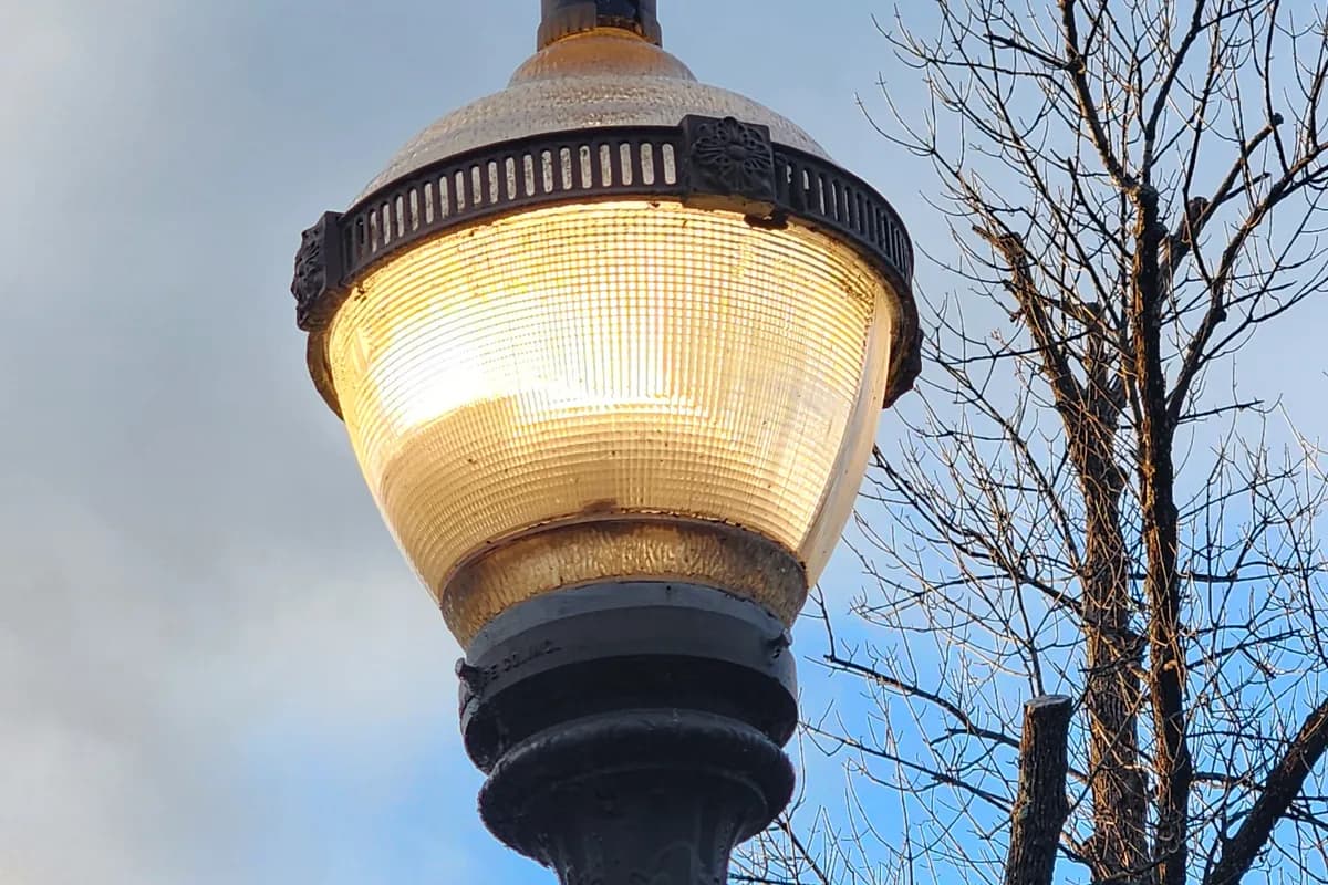 Decorative street lighting pole lit at dusk