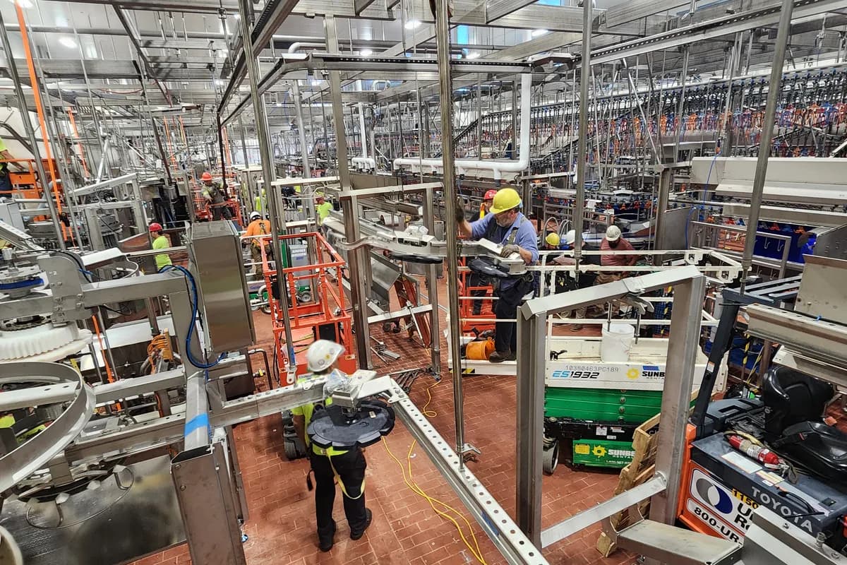 Crews in hard hats and high visibility working among stainless equipment in a food plant