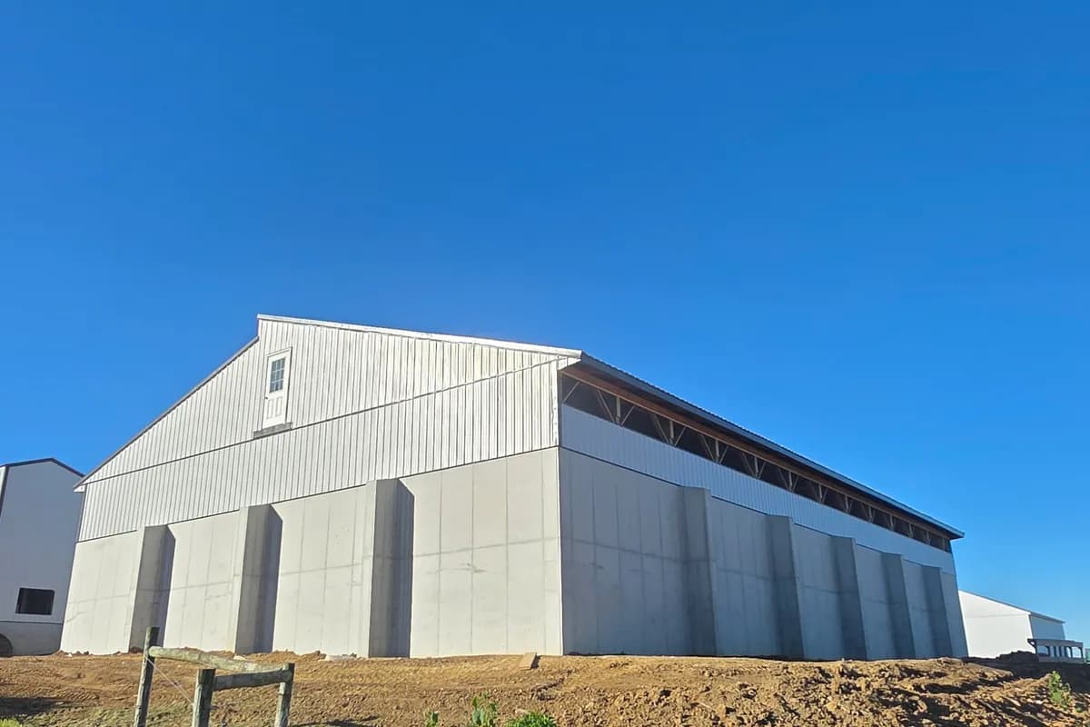 New poultry house seen from the yard, precast concrete stem walls below metal siding