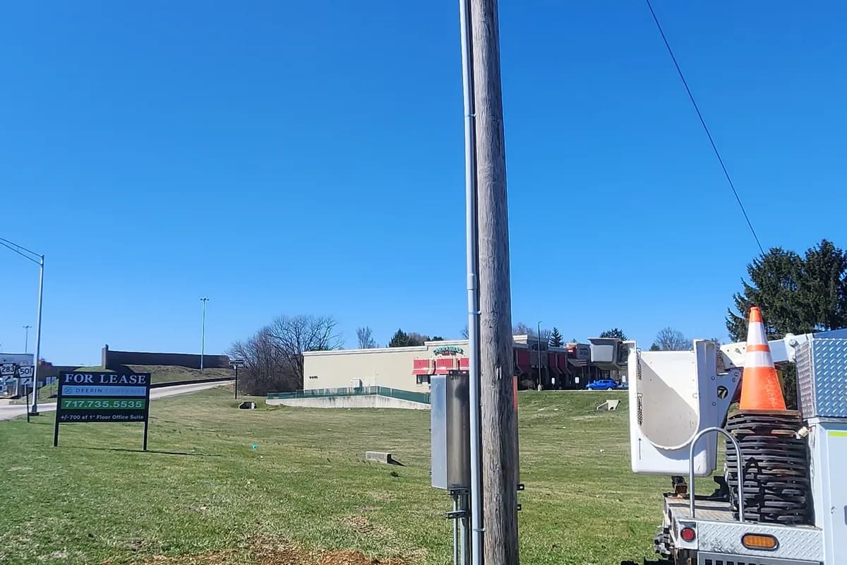 Newly set galvanised steel service pole in open ground with a bucket truck alongside