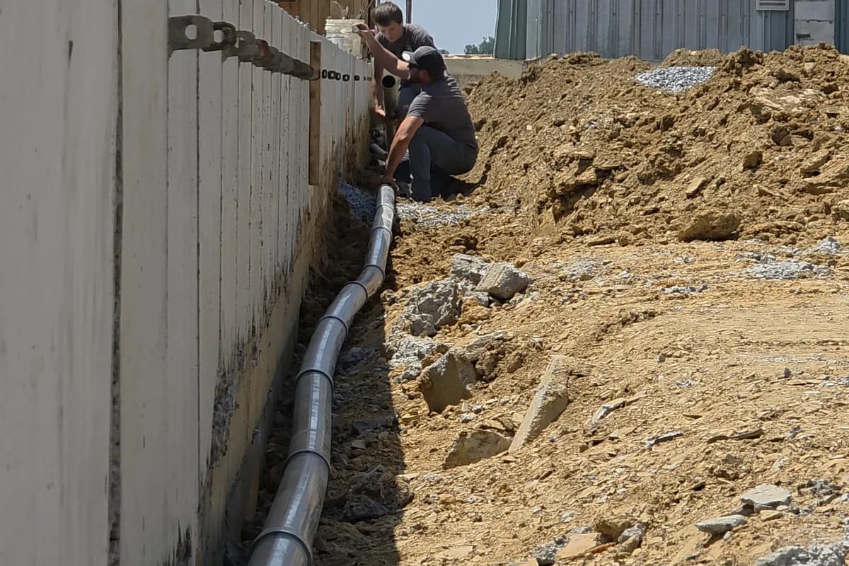 Crew working in an open trench alongside a farm building