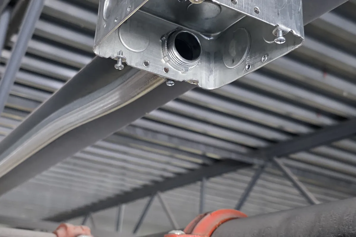 Overhead conduit and sprinkler pipework under a warehouse roof deck